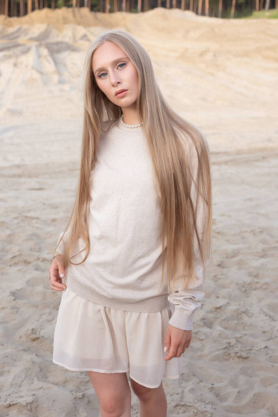 attrayant caucasien fille avec les cheveux longs et nu maquillage posant à l'extérieur sur le sable - Photo, image