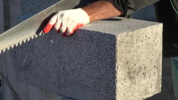 piłowanie piankowego bloku betonowego piłą ręczną. Bloki wykonane są z naturalnych materiałów i są przyjazne dla środowiska. koncepcja budowy własnego domu - Materiał filmowy, wideo