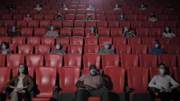 Diversos espectadores enmascarados viendo películas en el cine - Imágenes, Vídeo