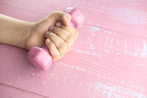 Close up of woman hand holding pink dumbbell. - Photo, Image