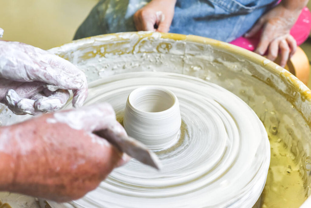 Дети учатся делать керамику в качестве хобби со своей бабушкой в керамической мастерской - Фото, изображение