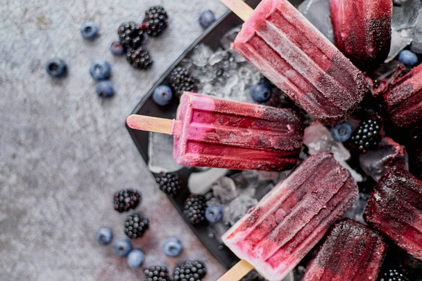 Forrest fruit ice cream on stick. Homemade healthy vegan snack. Placed on plate with ice - Foto, Imagem