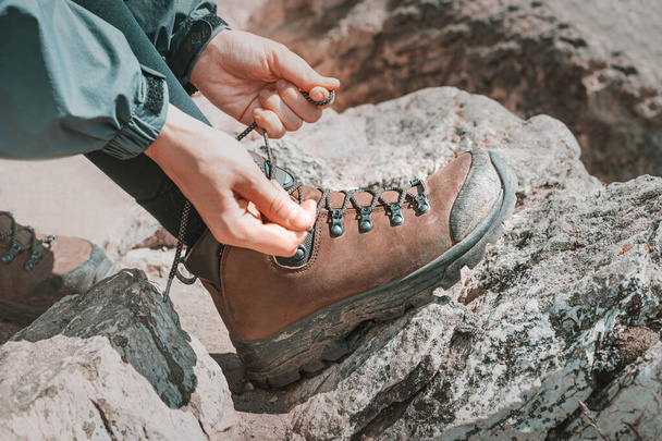 Девушка-туристка завязывает шнурки на обуви во время похода и отдыха в национальном парке в горах - Фото, изображение
