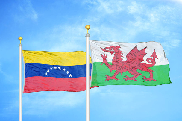 Venezuela a Wales dvě vlajky na vlajkových stožárech a modrá oblačná obloha pozadí - Fotografie, Obrázek