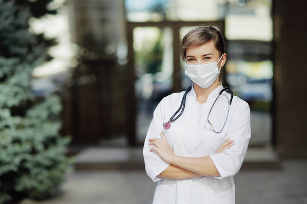Confident female doctor or nurse wearing a face protective mask. Safety measures against the coronavirus. Prevention Covid-19 healthcare concept. Stethoscope over the neck. Woman, girl. - Photo, Image