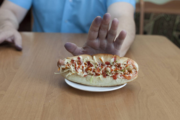 Un uomo rifiuta un hot dog perché non è cibo sano. Telaio orizzontale. - Foto, immagini