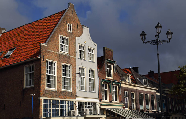 Gevels van historische huizen aan de Markt στο Delft met een donkere regenlucht - Φωτογραφία, εικόνα