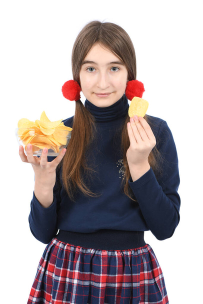 Předpubertální holka držící misku je plná bramborových lupínků. Izolované na bílém pozadí. Fotka ve vysokém rozlišení. Plná hloubka pole. - Fotografie, Obrázek