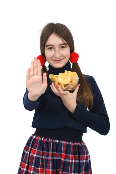 Předpubertální holka držící misku je plná bramborových lupínků. Izolované na bílém pozadí. Fotka ve vysokém rozlišení. Plná hloubka pole. Koncept výběru nezdravého jídla k jídlu. - Fotografie, Obrázek
