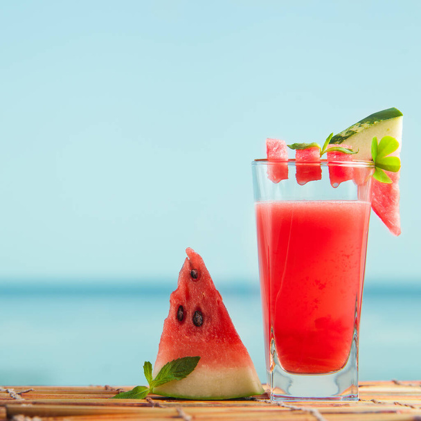 Fresh just squeezed watermelon drink with sea on background. Detox drink with seasonal fruits. Perfect cool beverage on hot summer day. - Foto, Imagen