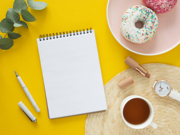 Una maqueta de la lista de tareas pendientes. Vista superior portátil en blanco, té y rosquillas en una mesa amarilla. Puesta plana - Foto, imagen