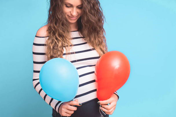 Pregnant woman tries to guess the boy or girl. Balloons as symbol of boy and girl. Gender of the unborn child concept. Copy space. - Fotografie, Obrázek