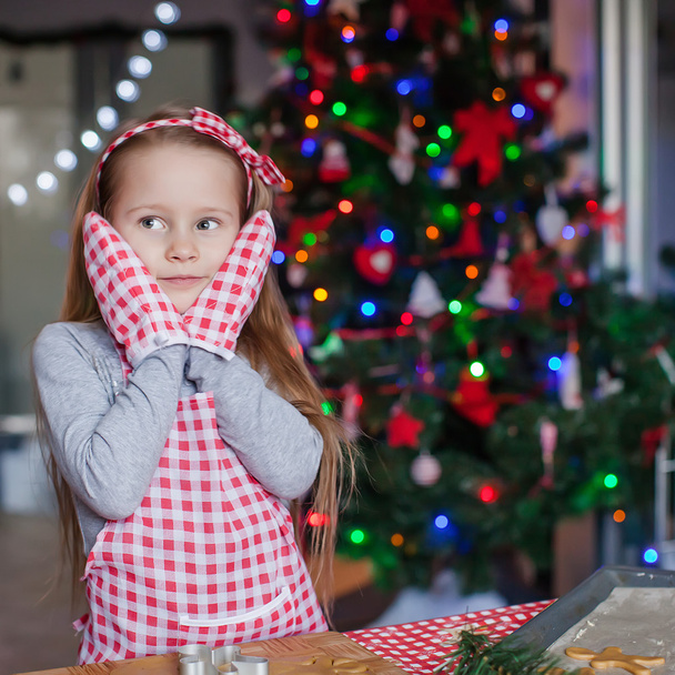 Чарівна маленька дівчинка в рукавичках випікає різдвяні торти
 - Фото, зображення