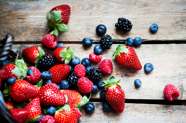 Mix of fresh berries in a basket on rustic wooden background - Foto, immagini