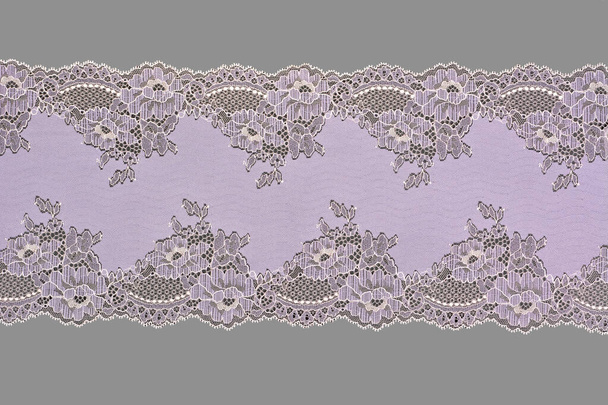 lilac beige color straight strip of lace fabric on gray background. Elastic silk nylon braid border. use clothes linen decoration. repeating pattern and interweaving threads. texture for websites - Photo, Image