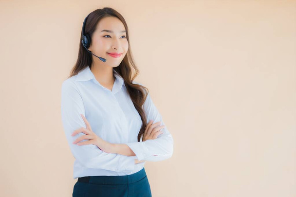 Portrait beautiful young asian business woman with headphone for call center on color isolated background - Photo, image