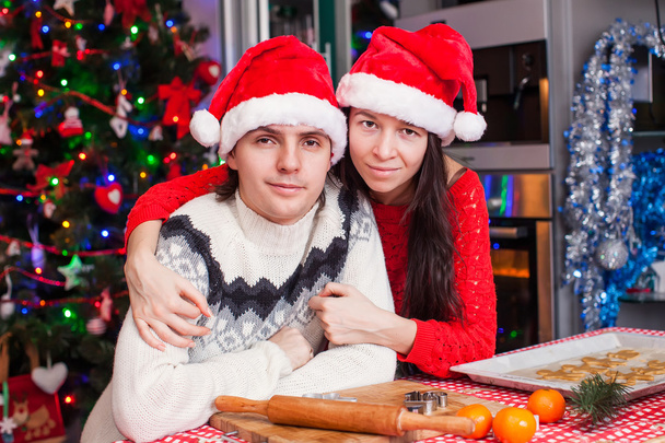 Porträt eines glücklichen jungen Paares, das zu Hause Weihnachtskuchen backt - Foto, Bild
