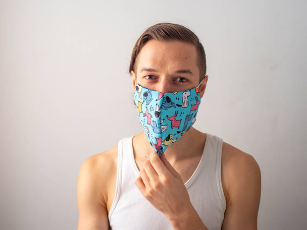 Junger blonder Kaukasier mit Gesichtsmaske und Hundedesign für Covid-19-Pandemie - Foto, Bild