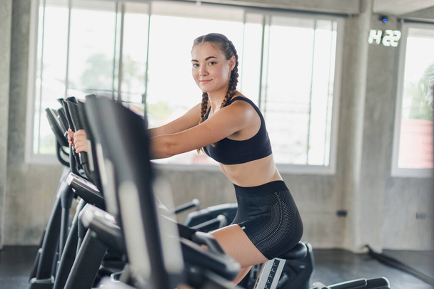 Athlete, woman, girl exercising, biking in the gym. She wears sports clothes to exercise. - 写真・画像