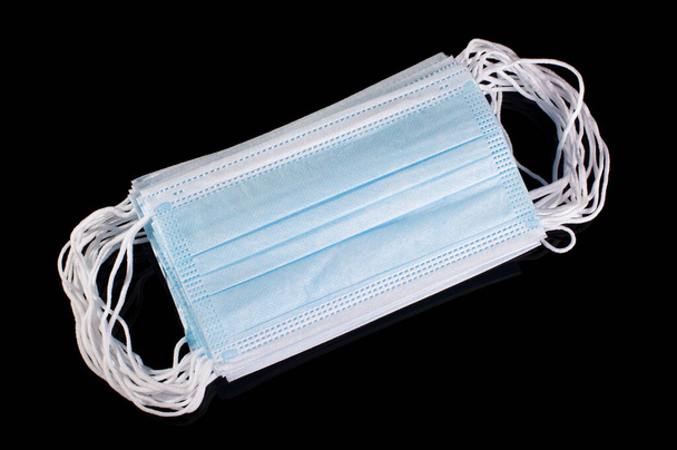 Pile of medical virus protection disposable face mask isolated on the black reflective background - Foto, imagen