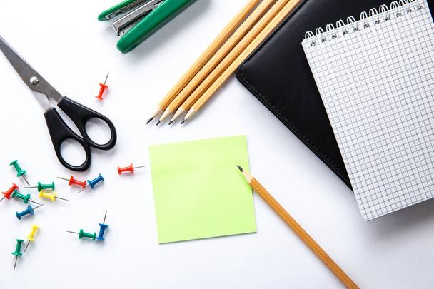 Stationery. Background of school or office accessories. Note, pencil, scissors, push pins, sticker for notes, stapler on white desk. Success and creative concept. Idea of a diligent study or work - Photo, Image