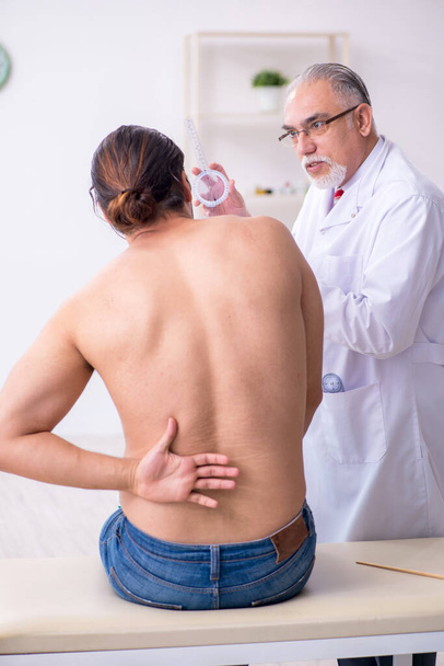 Young back injured man visiting experienced male doctor - Photo, Image