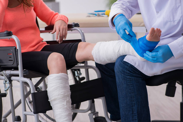 Young leg injured woman visiting old doctor traumatologist - Фото, изображение
