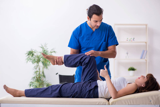 Injured woman visiting young male doctor osteopath - Foto, afbeelding