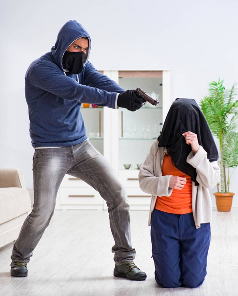 Armed man assaulting young woman at home - 写真・画像