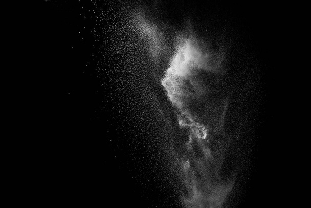 Замораживание движения частиц белой пыли на черном фоне. - Фото, изображение