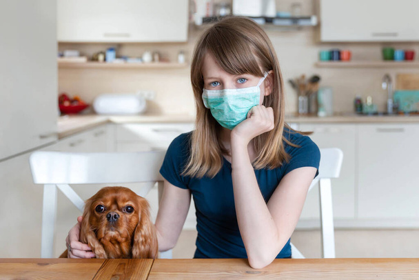 Девушка в защитной хирургической маске со своей собакой, концепция карантина - Фото, изображение
