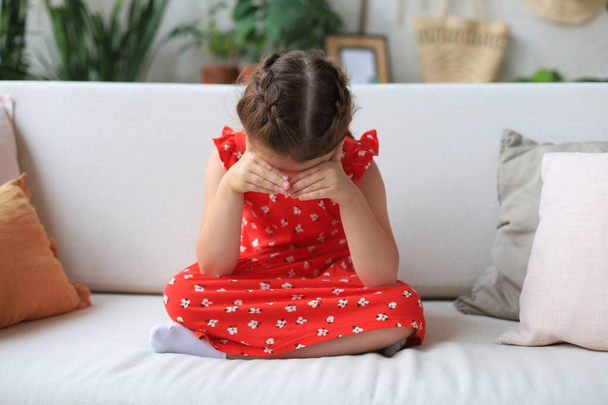 Sad little girl sitting on sofa alone at home - Valokuva, kuva