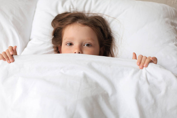 Cute child little girl woke up and lies in the bed - Foto, Bild