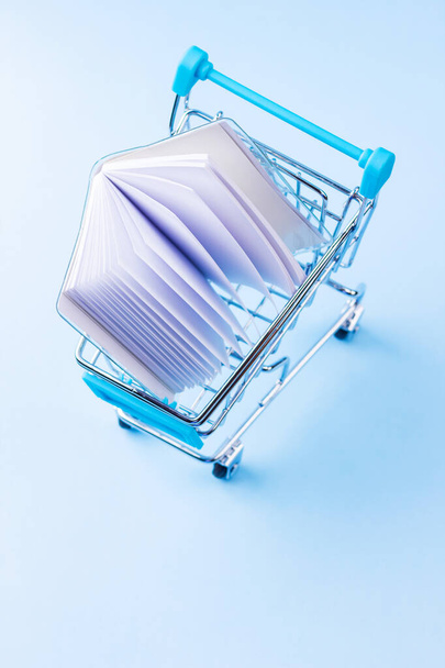 Shopping cart with school supply. School notepad with holographic cover. Purchase of school supplies for training. Back to school concept - Zdjęcie, obraz