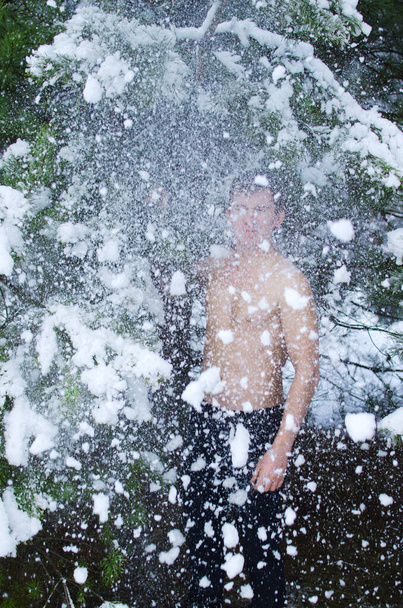 Junger Mann ohne Hemd im Winterwald streut Schnee - Foto, Bild