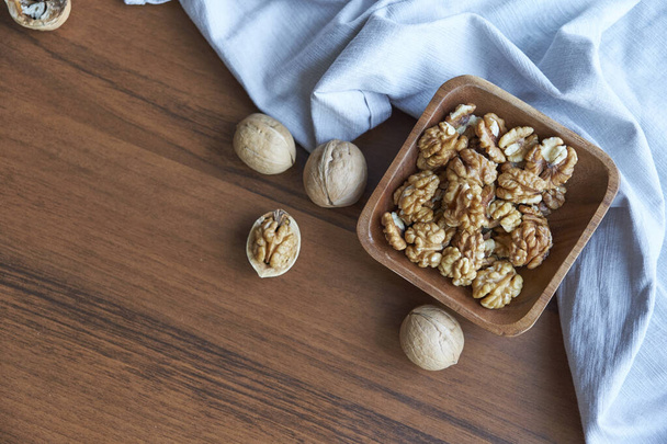 Walnuts kernels on dark desk with color background, Whole walnut in wood vintage bowl. - Foto, Imagem