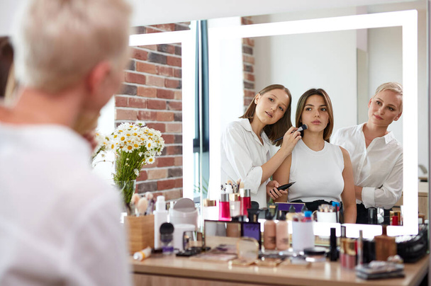stylists, make-up artists look at model on mirror - Фото, изображение