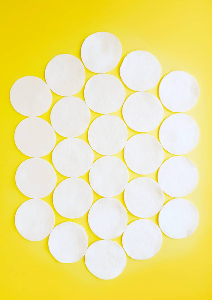 Cotton cotton discs on a yellow background. Personal hygiene and care. Medicine and cosmetology. - Foto, afbeelding