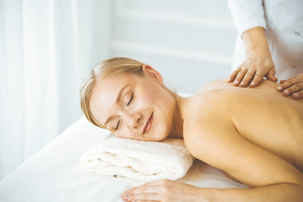 Beautiful happy woman enjoying back massage with closed eyes. Beauty and Spa salon concept - Foto, Imagen