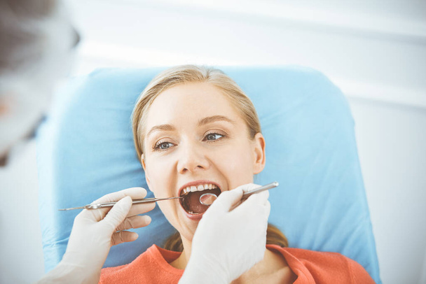 Happy smiling woman is being examined by dentist at dental clinic. Healthy teeth and medicine, stomatology concept - Foto, Bild