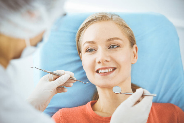 Happy smiling woman is being examined by dentist at dental clinic. Healthy teeth and medicine, stomatology concept - Фото, зображення