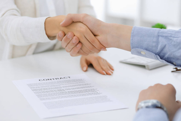 Business people shaking hands at meeting or negotiation after contract discussing. Businessman and woman handshake at office while sitting at the desk. Success concept - Photo, image