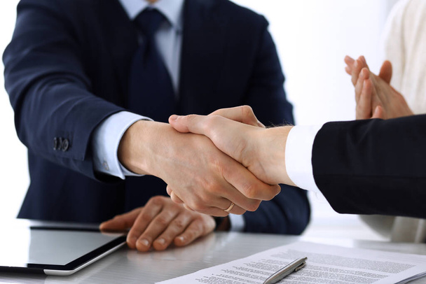 Business people shaking hands after contract signing at the glass desk in modern office. Unknown businessman with colleagues at meeting or negotiation. Teamwork, partnership and handshake concept - Photo, image