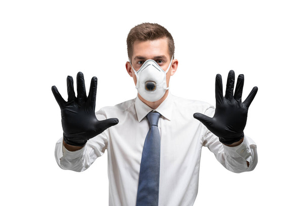Serious young businessman in gloves and protective mask showing stop sign. Isolated portrait. Covid 19 protection - 写真・画像
