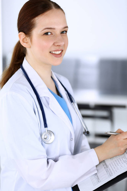 Doctor woman or intern student at work. Physician filling up medication history record while standing in emergency hospital office. Medicine and health care concept - Photo, image