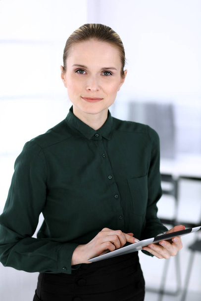 Business woman headshot in modern office. Secretary or female lawyer using tablet computer while standing straight. Business people concept - Zdjęcie, obraz