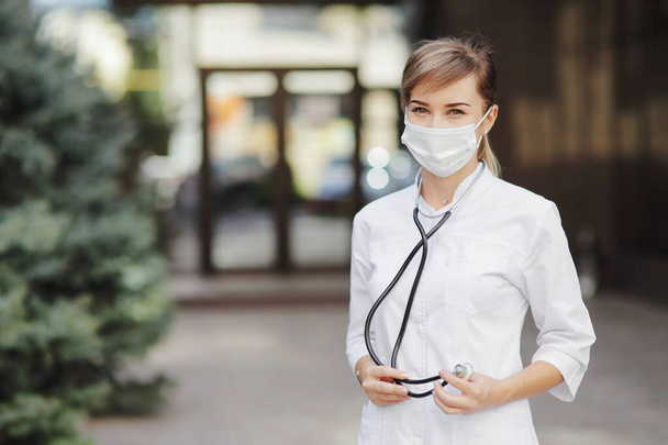 Confident female doctor or nurse wearing a face protective mask. Safety measures against the coronavirus. Prevention Covid-19 healthcare concept. Stethoscope over the neck. Woman, girl. - Photo, Image