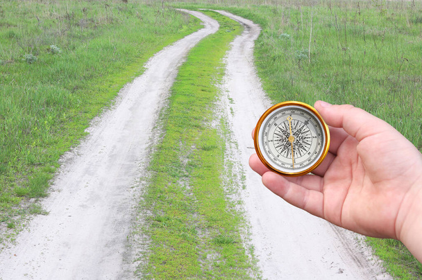 Старий класичний навігаційний компас в руці на тлі дороги як символ туризму з компасом, подорожі з компасом та активний відпочинок з компасом
 - Фото, зображення