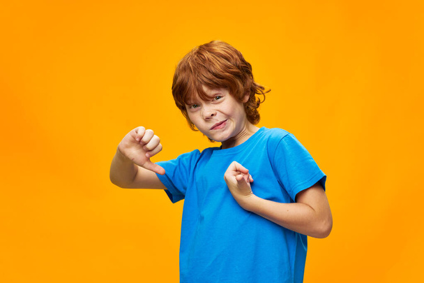 The red-haired boy on a yellow background points his finger at himself  - Fotoğraf, Görsel
