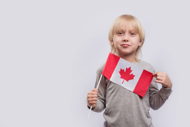 Young fair-haired boy holding flag of Canada. Education in Canada. - Foto, imagen